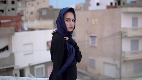 Junge Frau mit arabischem Kopftuch. Eine Frau läuft auf dem Dach. Auf dem Dach des Hauses vor dem Hintergrund arabischer Häuser. — Stockfoto