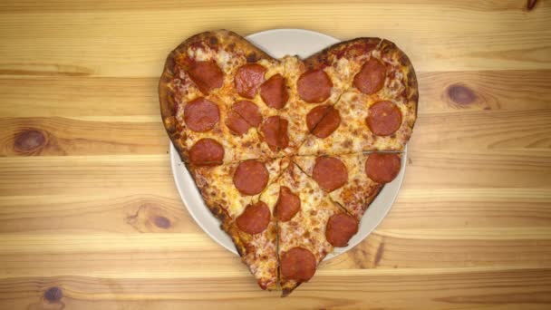 Pizza en forma de corazón para San Valentín. Joven toma una rebanada de pizza vista superior. — Vídeo de stock