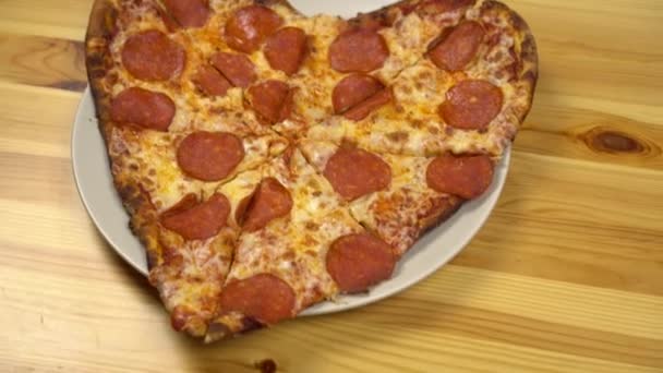 Pizza w kształcie serca na Walentynki. Młoda kobieta bierze kawałek pizzy.. — Wideo stockowe