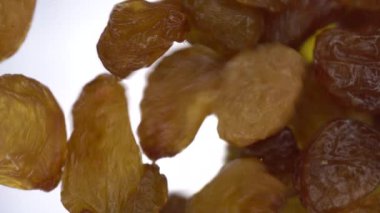 Kuru üzümler parlak beyaz arka planda cama düşer. Kuru üzümler makro alt görünüm.