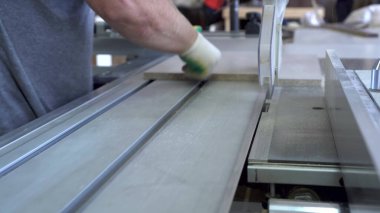 Bir adam mobilya üretim tesisinde tahta parçaları dairesel testere ile kesiyor..