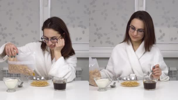 Una joven con un abrigo blanco está comiendo cereales y tomando café, soñoliento y alegre. Collage de dos pantallas como una niña está desayunando. — Vídeo de stock