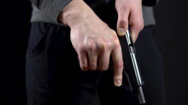 Haydut silahı yeniden doldurdu ve siyah arka planda duruyor. Yakın plan..