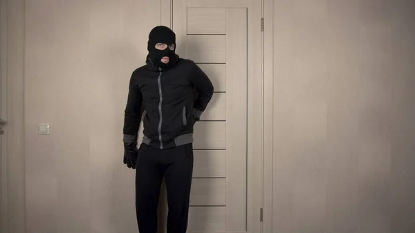 The robber climbed into the house. The masked bandit opened the door and went on toes. Stock Image