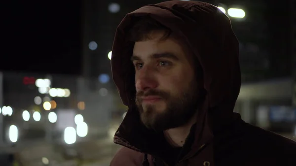 一个年轻人晚上站在外面的寒冷中，呼吸着暖暖双手. 免版税图库照片
