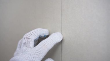 İnşaatçı, duvardaki tornavidayı kullanarak alçı taşı tahtasını kendi kendine tıkırdatıyor..