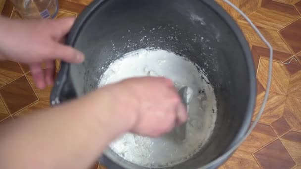 Stavitel míchá tmel s vodou v kbelíku na opravy. — Stock video
