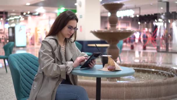 Молодая женщина в кафе с табличкой в руках на фоне фонтана. Украшение в кафе. — стоковое видео