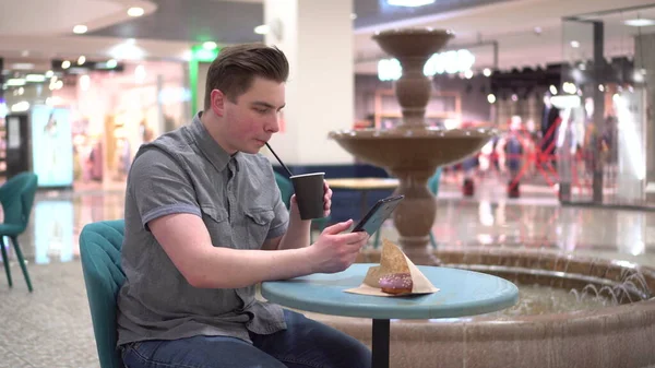 Молодий чоловік у кафе з табличкою в руках на фоні фонтану. Декорування в кафе . — стокове фото