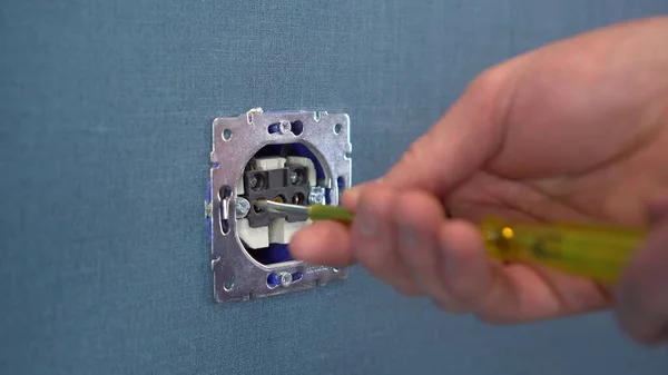 Electrician repairing a wall outlet with a screwdriver. Close-up. — Stock Photo, Image