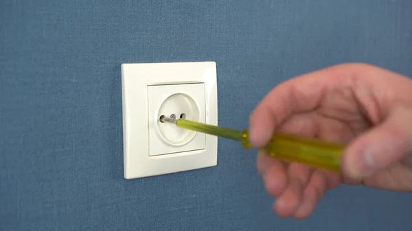 An electrician disassemble the socket on the wall with a special screwdriver. Close-up. — Stock Photo, Image
