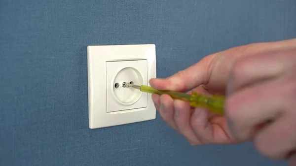 An electrician disassemble the socket on the wall with a special screwdriver. Close-up. — Stock Photo, Image