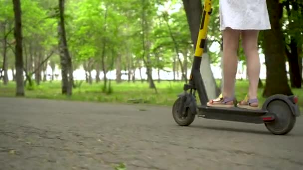 Молода жінка в білій сукні їде на спільному електро скутері в парку. Вид знизу . — стокове відео