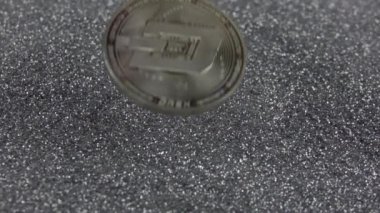 Dash kripto para birimi gümüş parıltıların üzerine düşer. Gerçek metal para. Yavaş çekim 500fps.