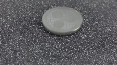 Dalgalanan kripto para gümüş parıltıların üzerine düşer. Gerçek metal XRP madeni para. Yavaş çekim 500fps.