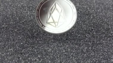 EOS kripto para birimi gümüş parıltıların üzerine düşer. Gerçek metal para. Yavaş çekim 500fps.