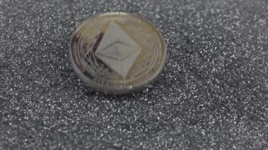 Ethereum kripto para birimi gümüş parıltıların üzerine düşer. Gerçek metal Eth sikkesi. Yavaş çekim 500fps.