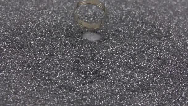 El anillo de bodas de oro cae sobre lentejuelas de plata. Cámara lenta 500 fps. — Vídeos de Stock