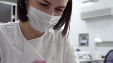 Profesyonel bir manikürcü matkapla eski tırnakları kesiyor. Manikür salonundaki çivi bakımı..