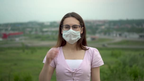 Een jonge vrouw met een bril doet haar medisch masker af en ademt vrij. Einde van de pandemie. — Stockvideo