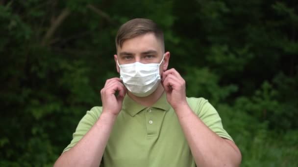 Mladý muž si sundá lékařskou masku a hodí ji do kamery. Muž v přírodě v masce. Zpomalený pohyb. — Stock video