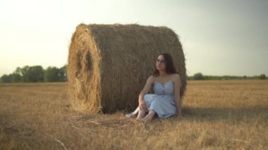 Genç bir kadın bir tarlada samanlığın yanında oturuyor ve bir arı ona doğru uçuyor. Gözlüklü ve mavi elbiseli bir kız eşek arısından el sallıyor. Kamera yakınlaşıyor..