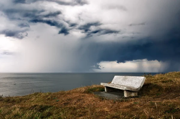 Bench on cliff with storm over sea — Stock Photo, Image