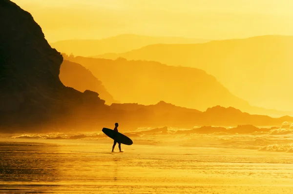 Surfeur entrant dans l'eau au coucher du soleil brumeux — Photo