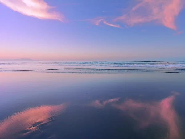 Meer bei Sonnenuntergang mit Wolkenreflexionen auf Sand — Stockfoto