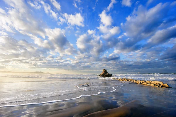 Rock in Sopelana beach with beautiful clouds — Stock Photo, Image