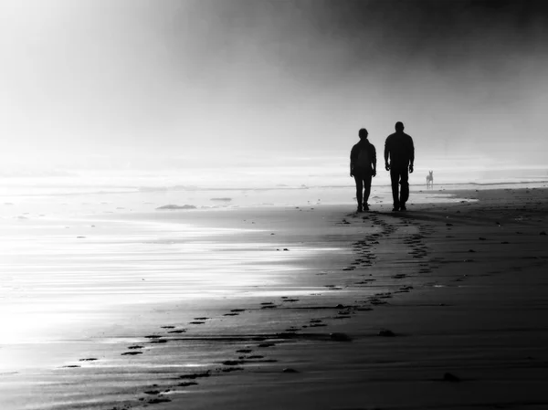 Pareja caminando en la playa brumosa — Foto de Stock