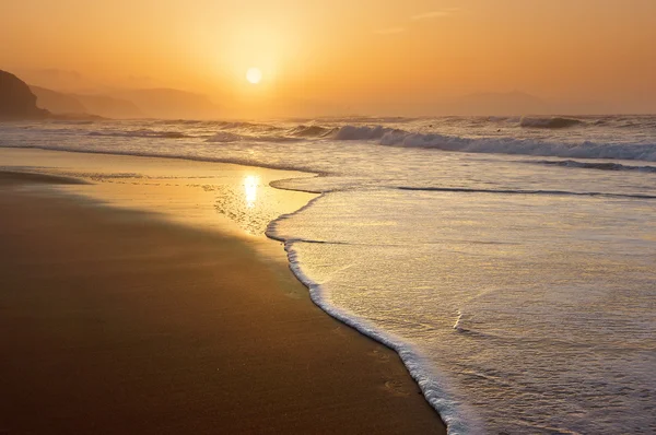 Beach at sunset with wave foam — Stock Photo, Image