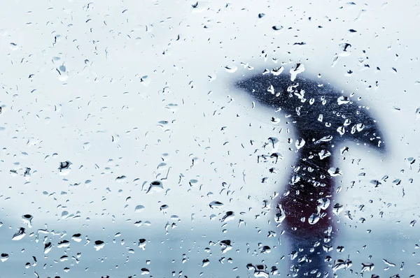 Gotas de lluvia en la ventana con persona con paraguas — Foto de Stock