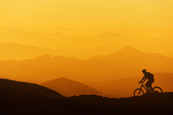 Biker riding on mountain silhouettes background — Stock Photo, Image