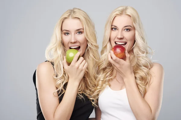 Blonde twins eating apples — Stock Photo, Image