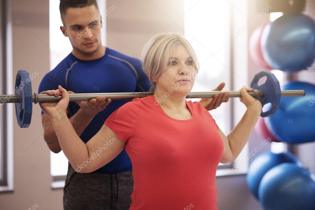Supporting instructor exercising with mature woman
