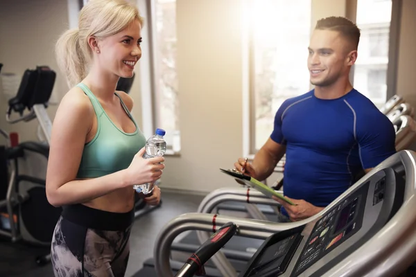 Mulher e seu personal trainer no ginásio — Fotografia de Stock