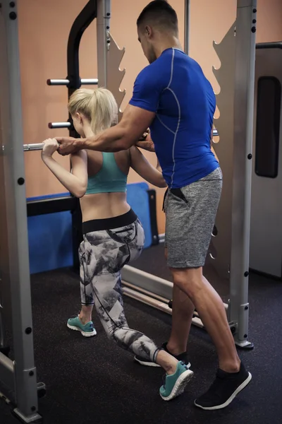 Fitnesstrainerin hilft Frau im Fitnessstudio — Stockfoto