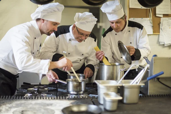 Tre uomini impegnati nella cucina commerciale — Foto Stock