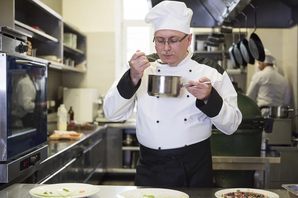 Chef sampling one of his meal — Stock Photo, Image