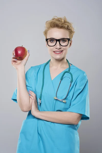 Женщина-дантист держит яблоко — стоковое фото