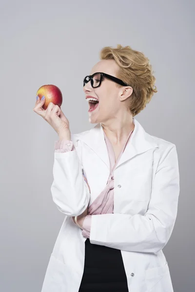 Dentista fêmea mordendo maçã deliciosa — Fotografia de Stock