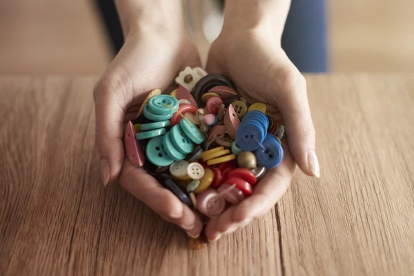 Händerna fulla av färgglada knappar — Stockfoto