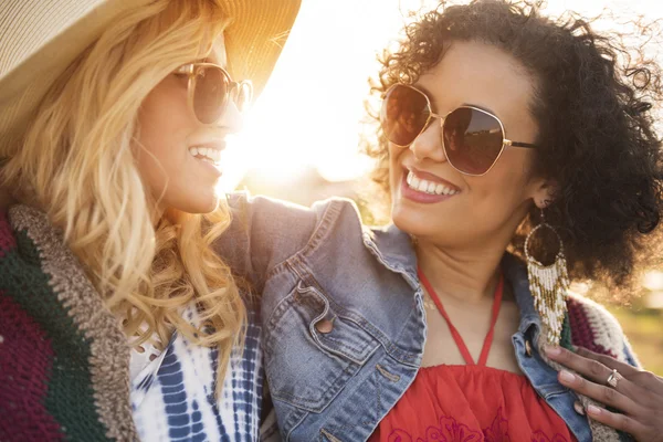 Mujeres sonriendo y abrazándose al atardecer — Foto de Stock