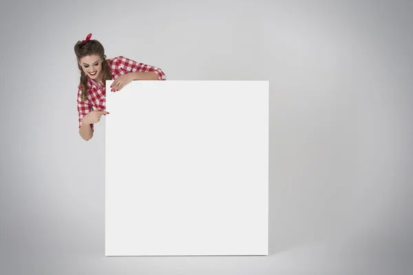 Pin up girl pointing a white placard — Stock Photo, Image