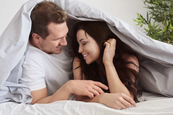 Casal passando a manhã sob o edredom — Fotografia de Stock