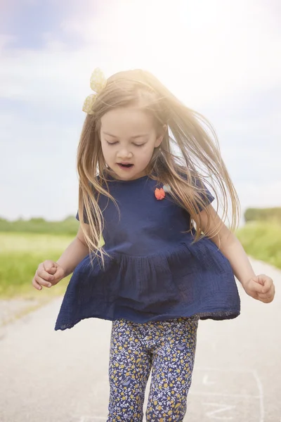 Маленькая девочка прыгает по дороге — стоковое фото