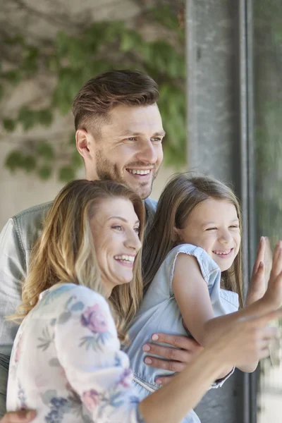 Jeune famille regardant à travers le verre — Photo