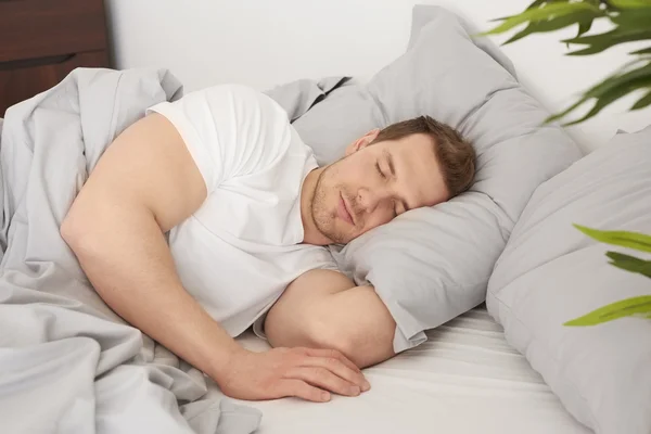 Homem dormindo na cama confortável — Fotografia de Stock