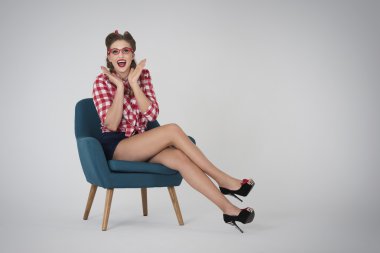 Pin up girl sitting in blue armchair clipart